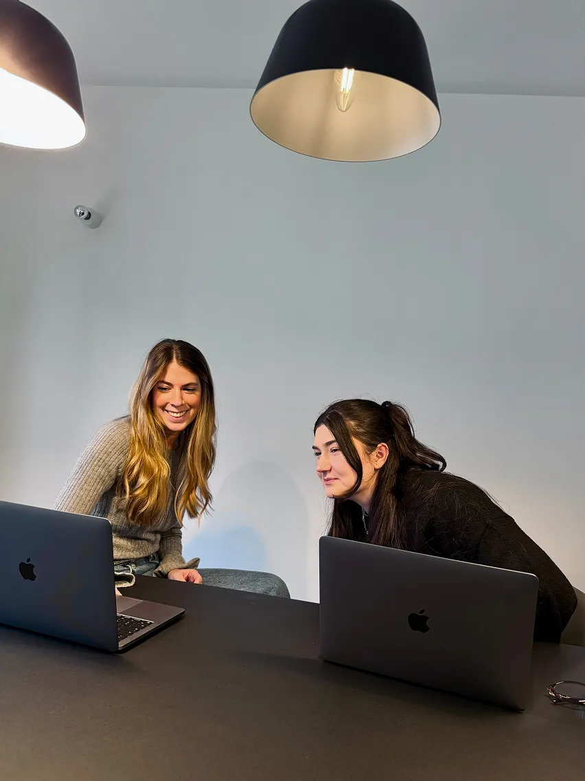 Fanus im Meeting mit einer Kollegin. Beide konzentriert und gut gelaunt am Laptop im Düsseldorfer Office von appsoluts.